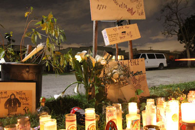 Photo: The Nava/Garcia memorial outside Salvador Medina's house -- the scene of the crime -- in Exposition Park.  A caricature drawn by graffiti artist "Fiber" next to a half-empty bottle of Patron, flowers, candles and other mementos. Credit: Mary Slosson