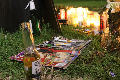Photo: An opened Corona and assortment of cigarettes flank the candlelit memorial for Alfonso Nava and Diego Garcia. Credit: Mary Slosson
