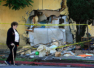 Photo: A woman passes the scene where a 19-year-old woman and her 10-day-old baby were killed when the infant's father drove his vehicle into their home. Credit: Mark Boster / Los Angeles Times