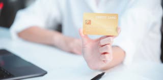 A person holding a gold credit card in their hand.