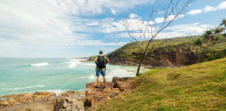 A person standing on a cliff overlooking the coastline in Australia.
