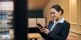 A woman in a suit accessing her Bluevine Business Checking account via her mobile phone.