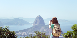 A person wearing a backpack taking a picture of the scenery in Brazil.