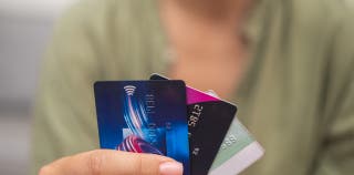 A woman holding three credit cards fanned out in front of her