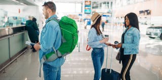 Three tourists preparing to check their luggage at an airport using TSA PreCheck.