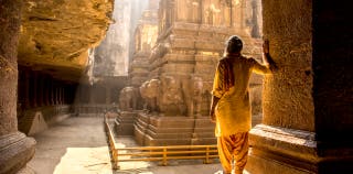A person standing in a stone temple in India.