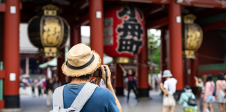 A person in hat taking pictures of the sights in Japan.