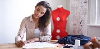 A female sole proprietor designs clothes for her small business.