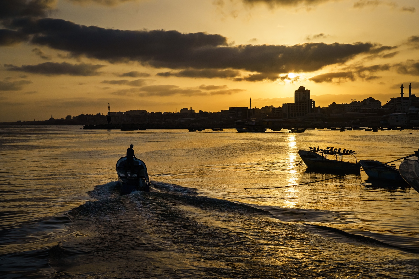 A motor boat heads out to sea as sun sets on Gaza's coastline