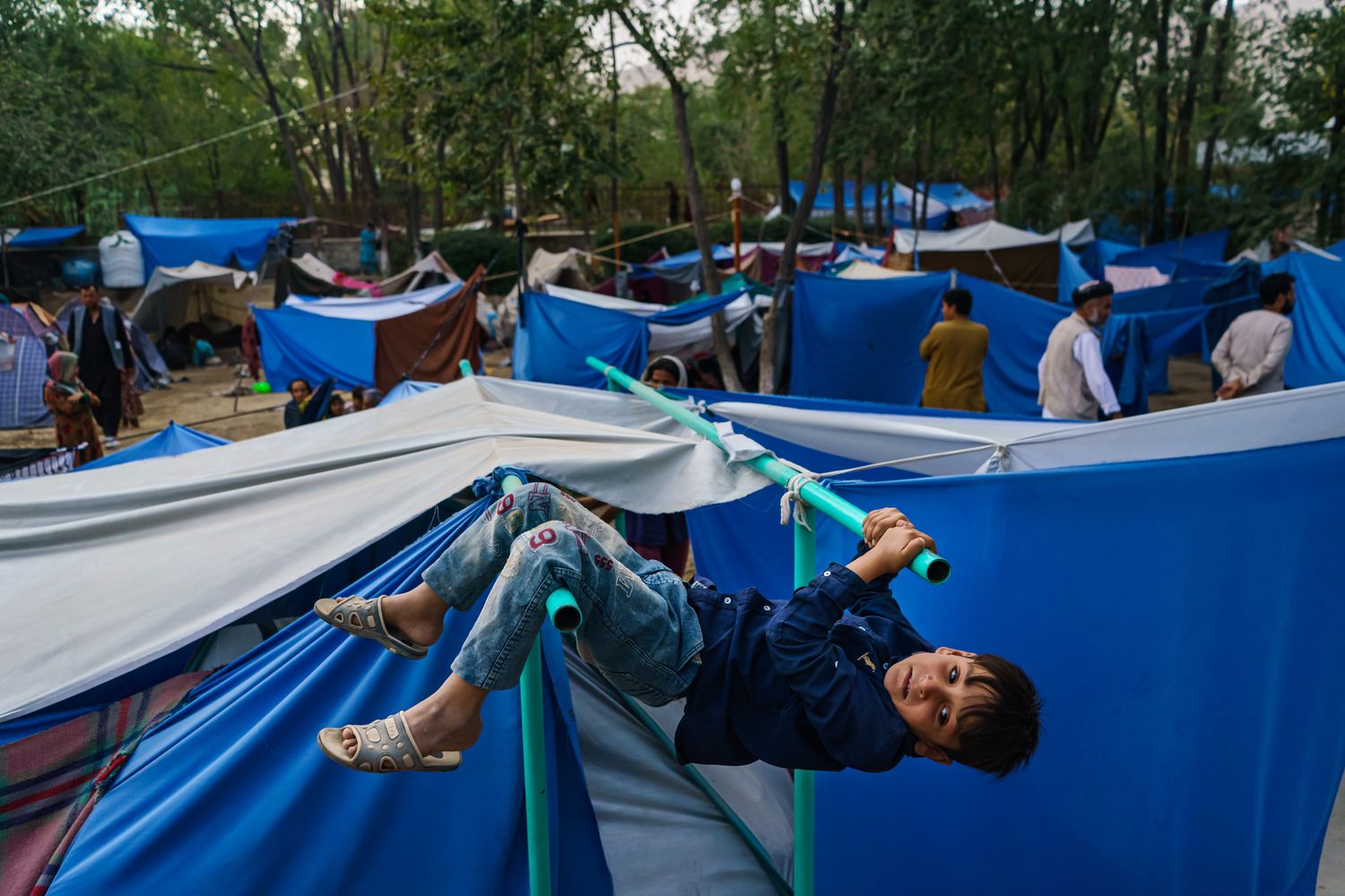 A child hangs from a pole holding up a tent.