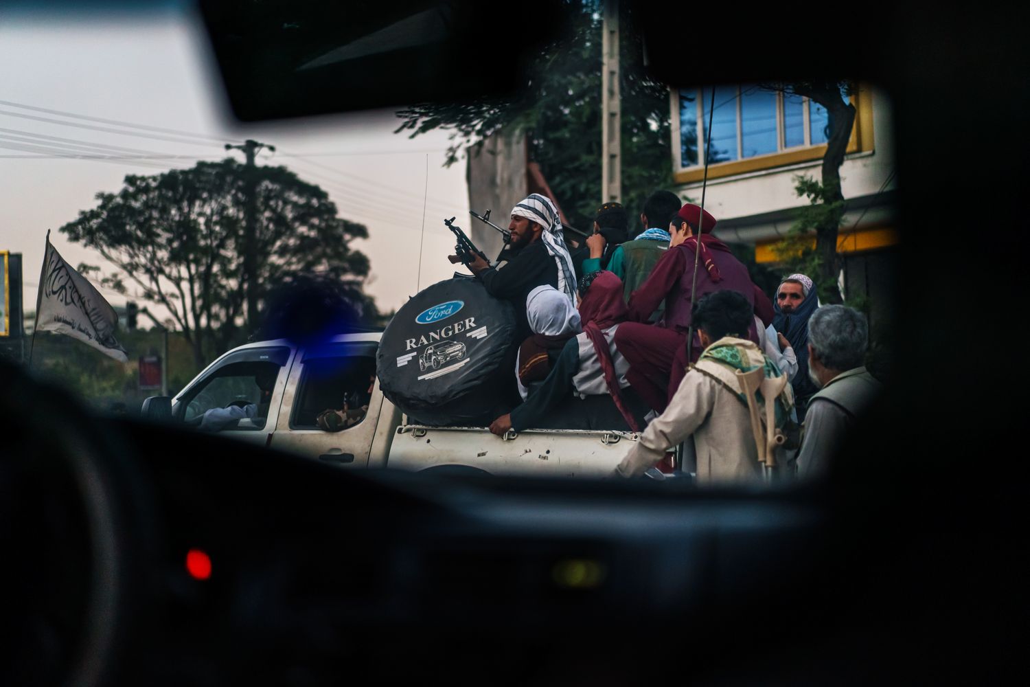 A view through a car window of Taliban members piled in a truckbed.
