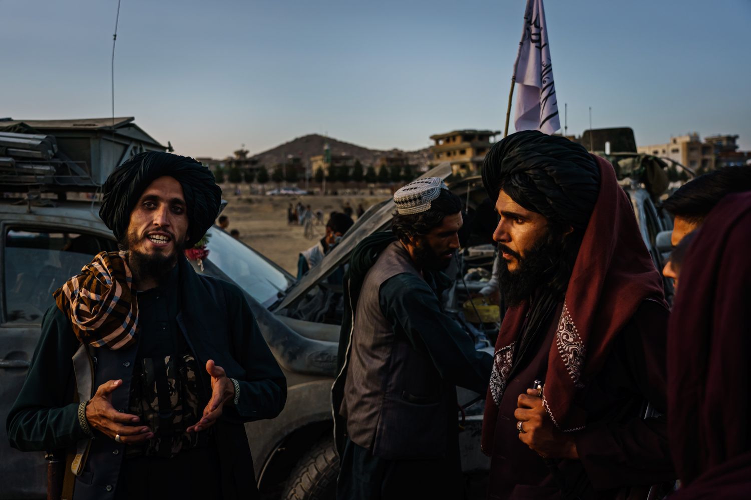 Taliban members standing outside watching one member speak.