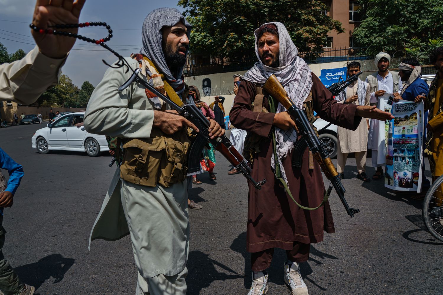 Two men carrying rifles while patrolling in the middle of a road.