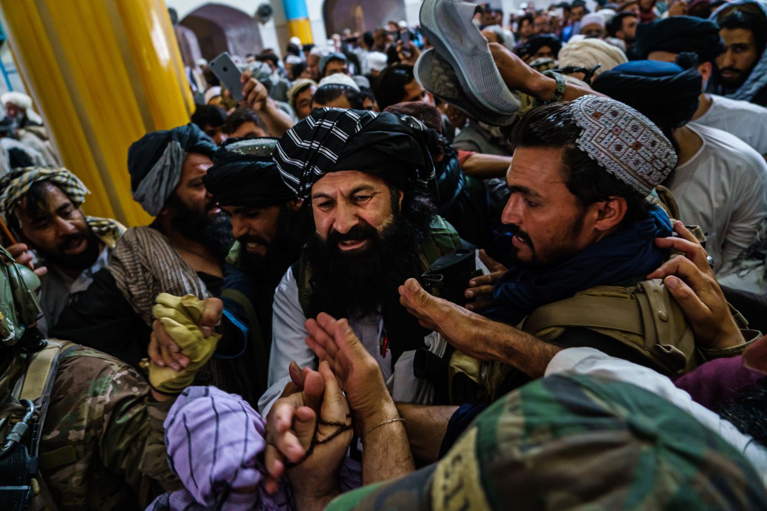Afghans reach out to greet a man in the center of a throng of people.