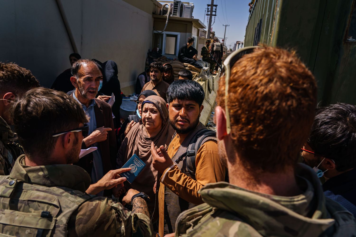 Men and women show their passports and speak with soldiers.