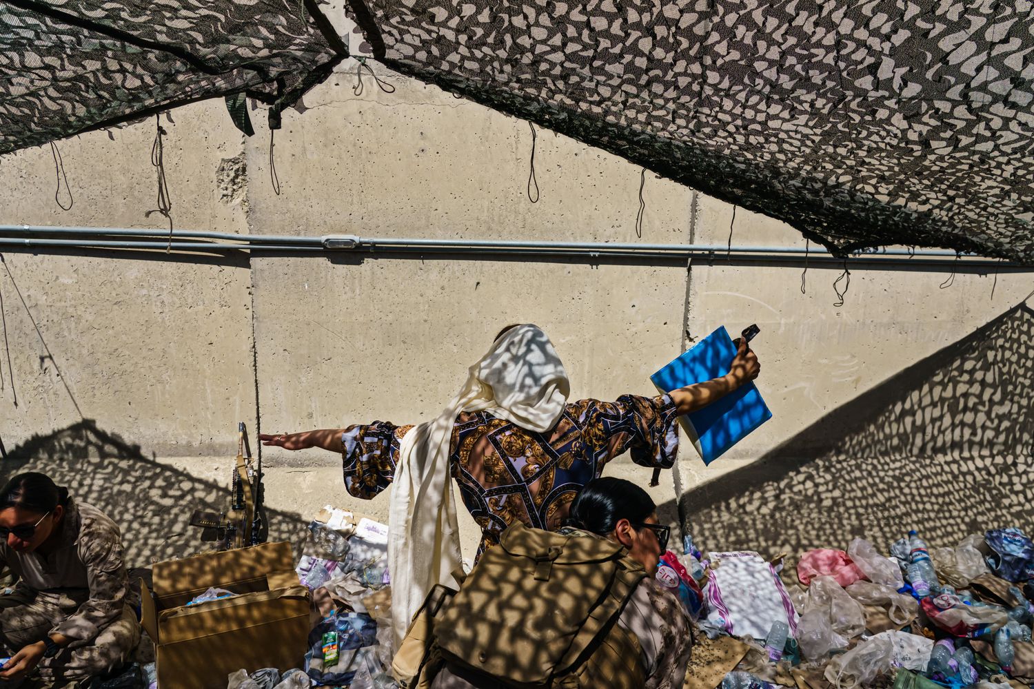 A Marine searches a woman in a tented area.