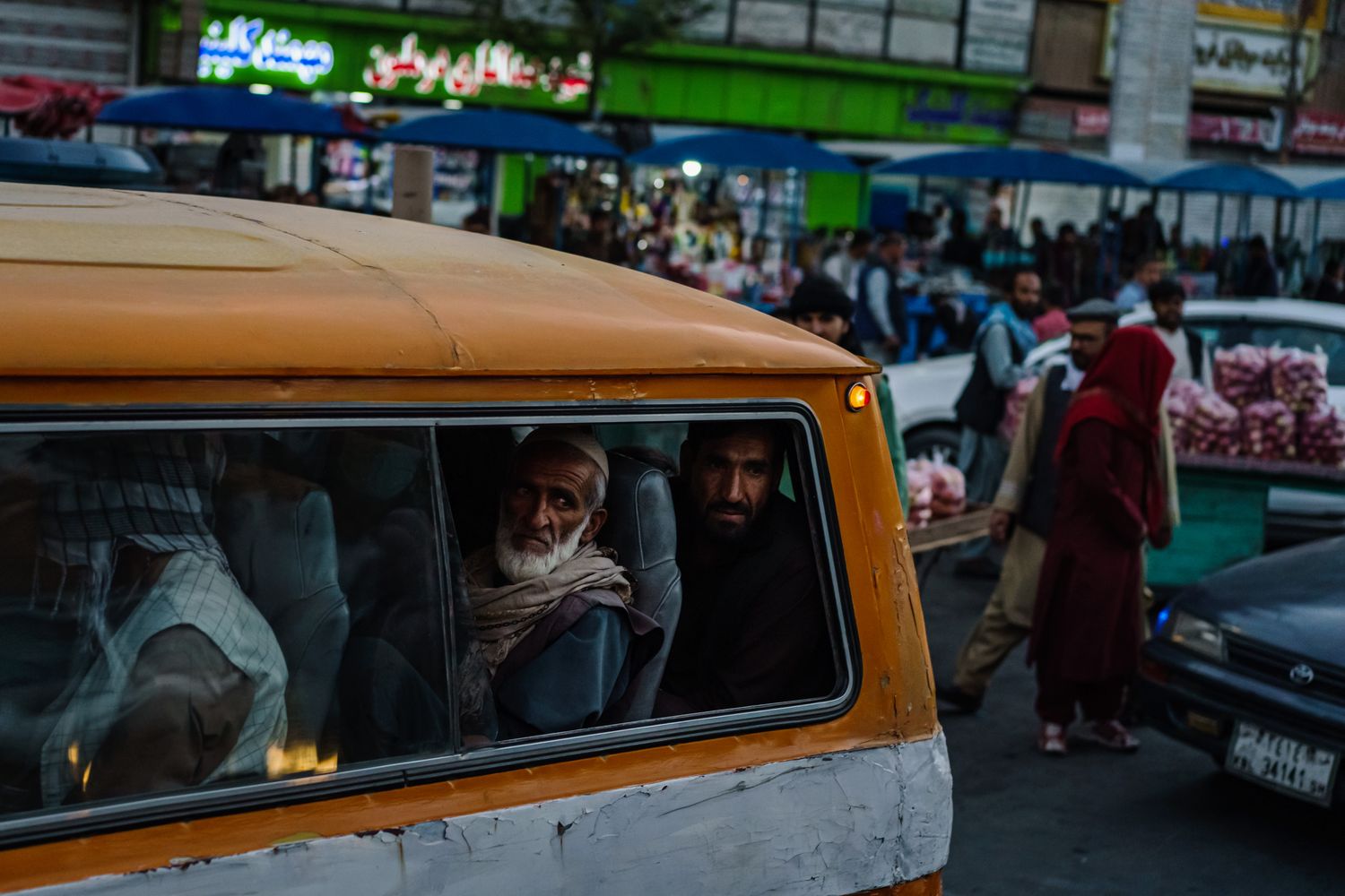 Two men peek outside the window of a van in traffic.