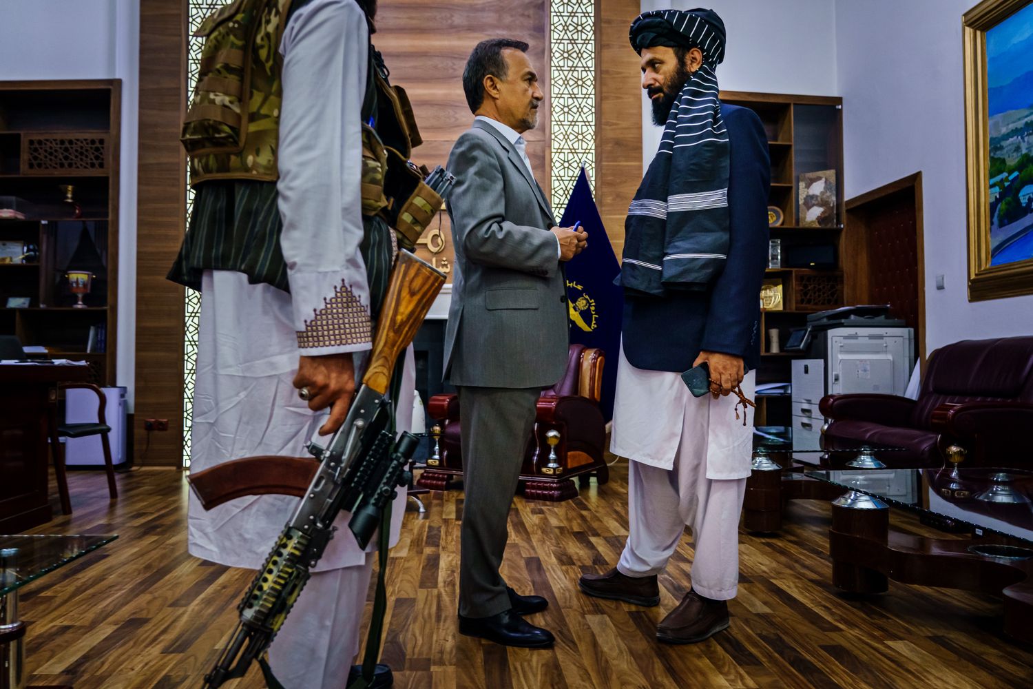 A Taliban fighter on the right speaks with a man in a suit at left.
