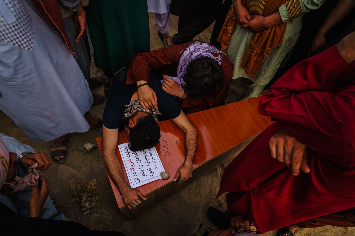 A man weeps as he embraces a coffin.