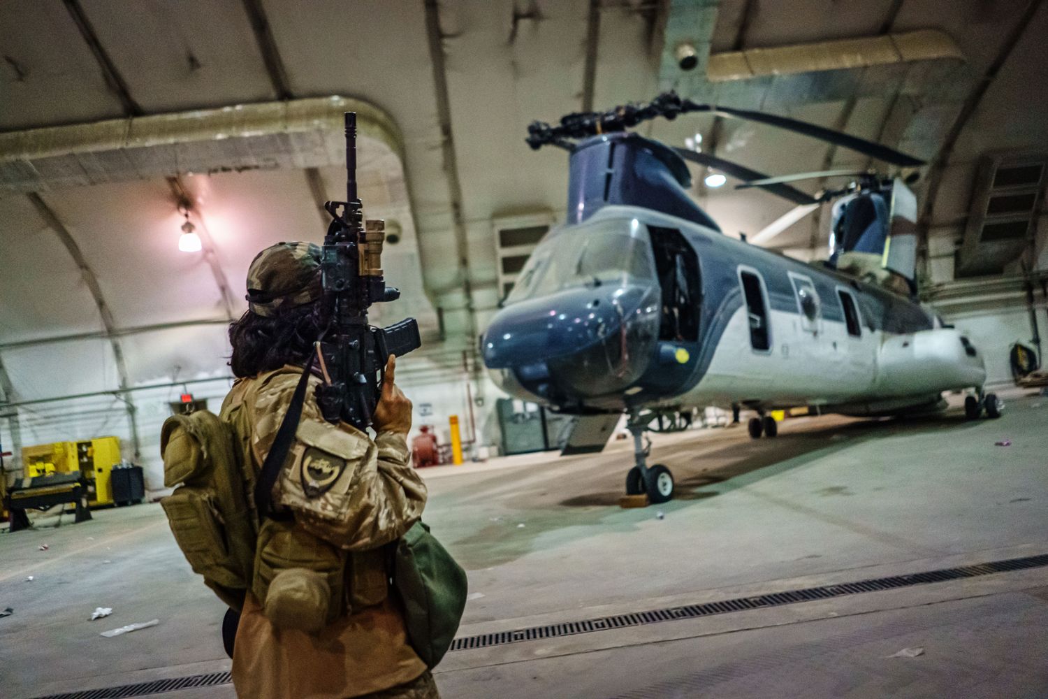 A Taliban fighter holding a rifle looks at a U.S. aircraft.