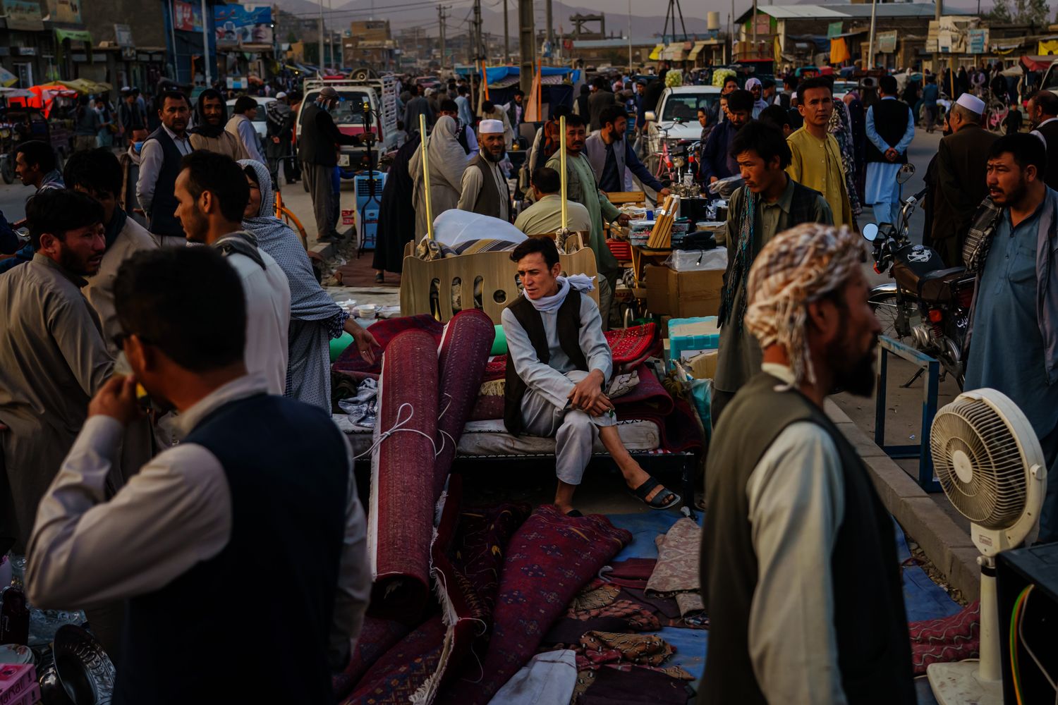 A man seated in the middle of a bustling market.