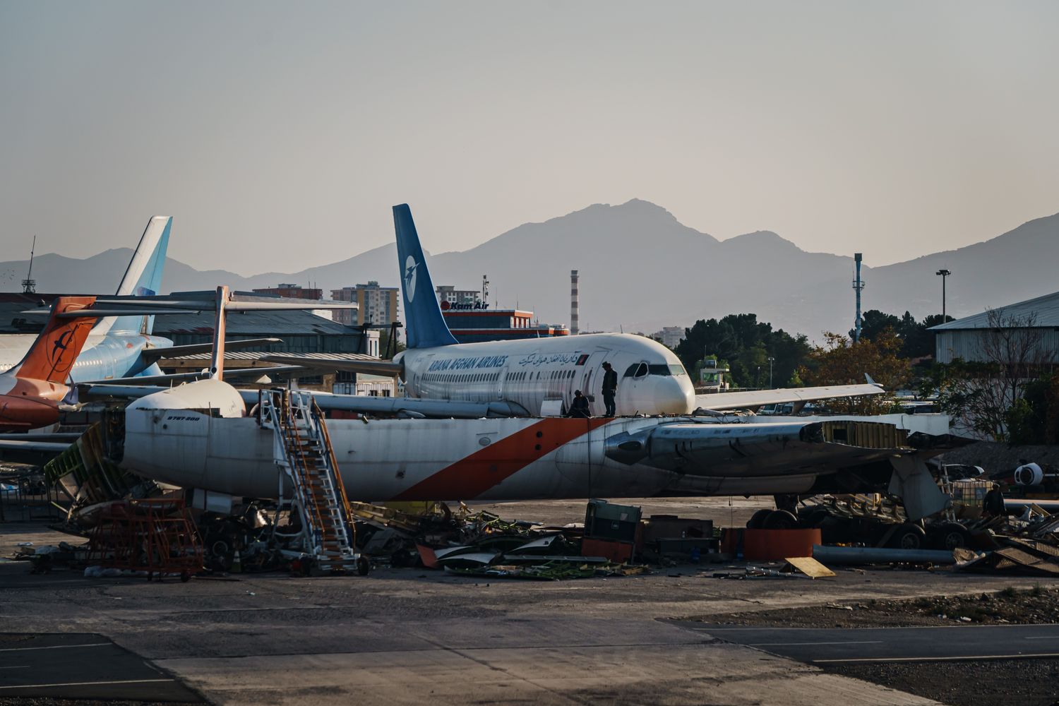 People standing on a damaged plane with debris underneath.