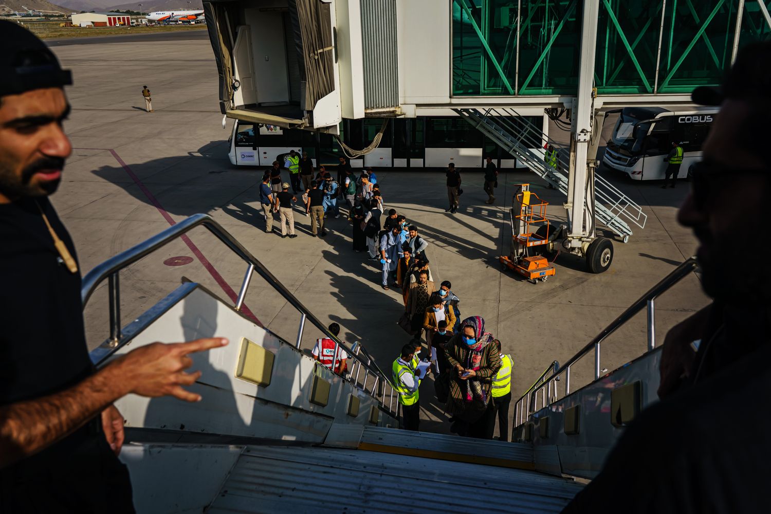 A view from the door of a plane showing a line of passengers waiting to board.
