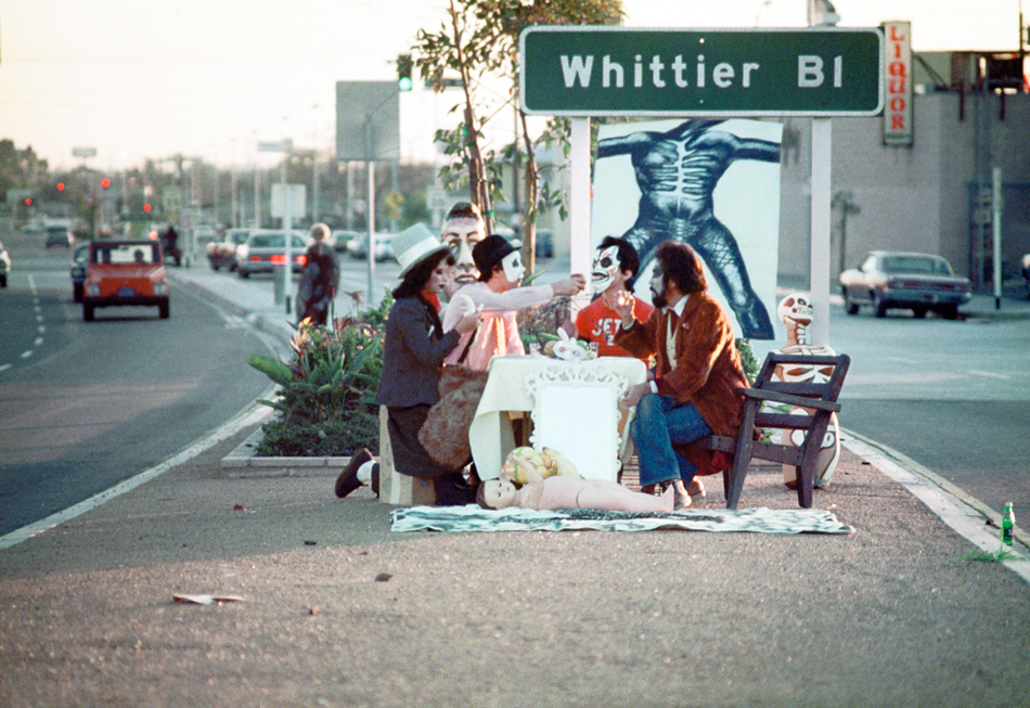 “First Supper (After A Major Riot),” 1974. Photograph by Harry Gamboa Jr. shows the members of the art collective Asco staging a performance in a median on South Arizona Ave in East Los Angeles.