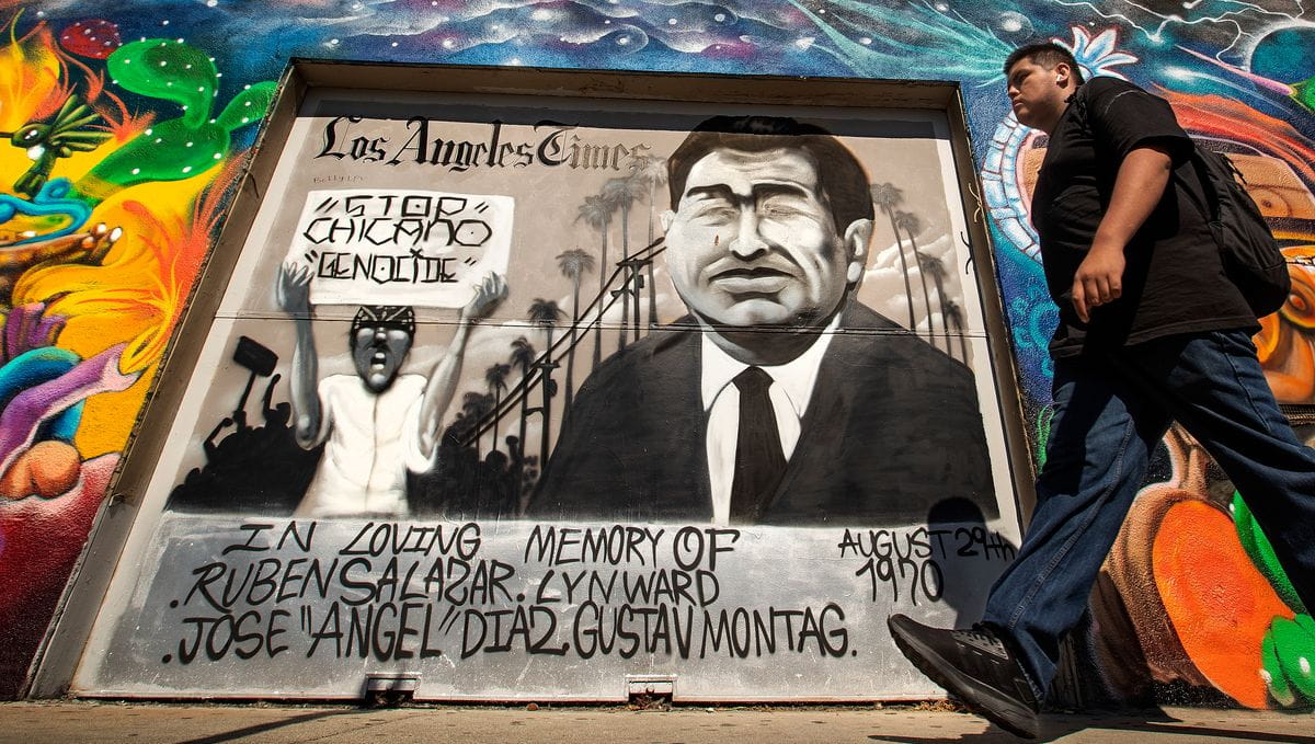 A mural in East Los Angeles shows an image of Ruben Salazar and of someone carrying a sign that says Stop Chicano Genocide.