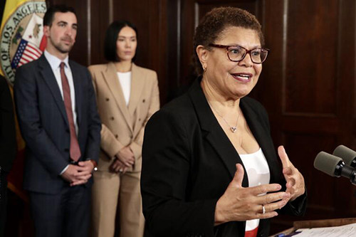 Mayor Karen Bass, standing in front of a mic, unveils her proposed city budget.