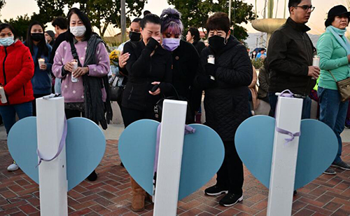 A woman is comforted while grieving as she reads the names of eleven people killed in a mass shooting