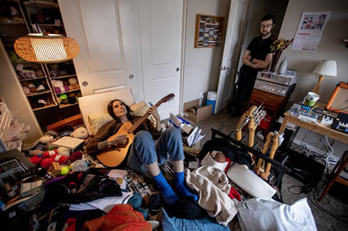 Courtney Garvin, who got sick with COVID in March 2020 and now has long COVID, plays guitar in her room.