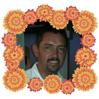 Foto de Javier Mendoza adentro de un borde de cempasĂșchiles anaranjados, amarillos y rosas