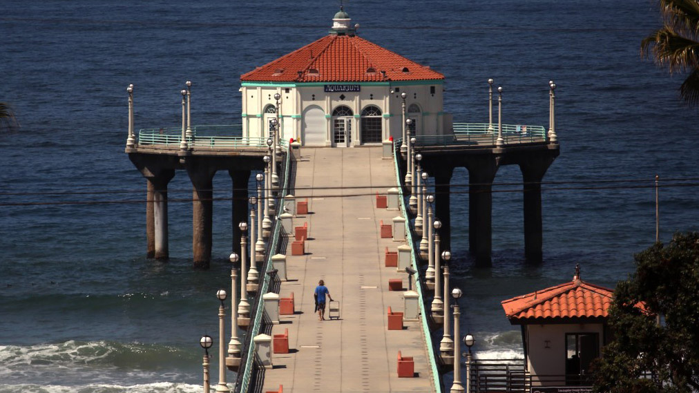 A lone figure walks onto the closed pier in Manhattan Beach. (Genaro Molina / Los Angeles Times)