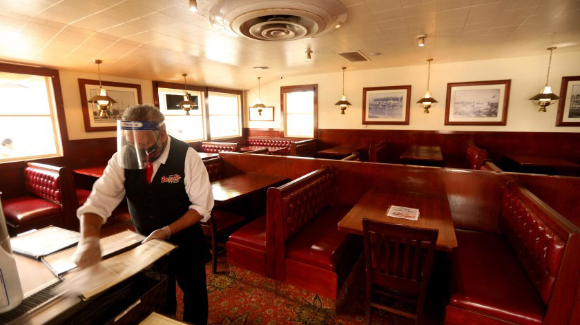 A staff member cleans menus at an empty Du-par’s restaurant at the Original Farmers Market in Los Angeles. (Genaro Molina / Los Angeles Times)