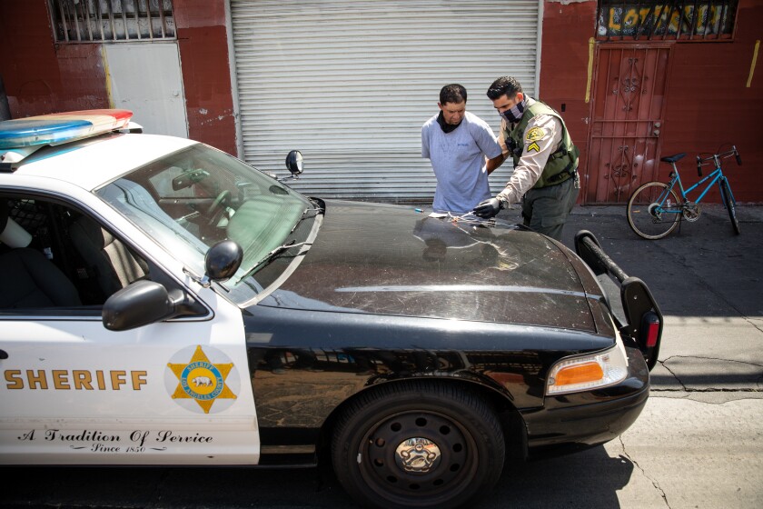 Los Angeles County Sheriff's Deputy Manan Butt searches a man who was on probation.