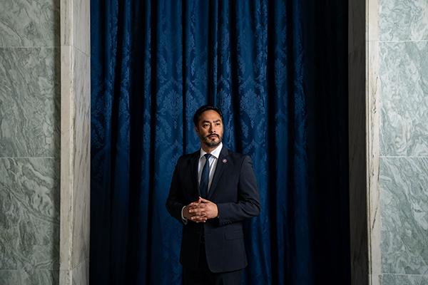Rep. Joaquin Castro (D-TX) poses in front of a blue curtain. This is a link to another story.