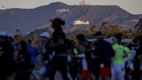 Runners pass in front of the Hollywood Sign and Griffith Park Observatory