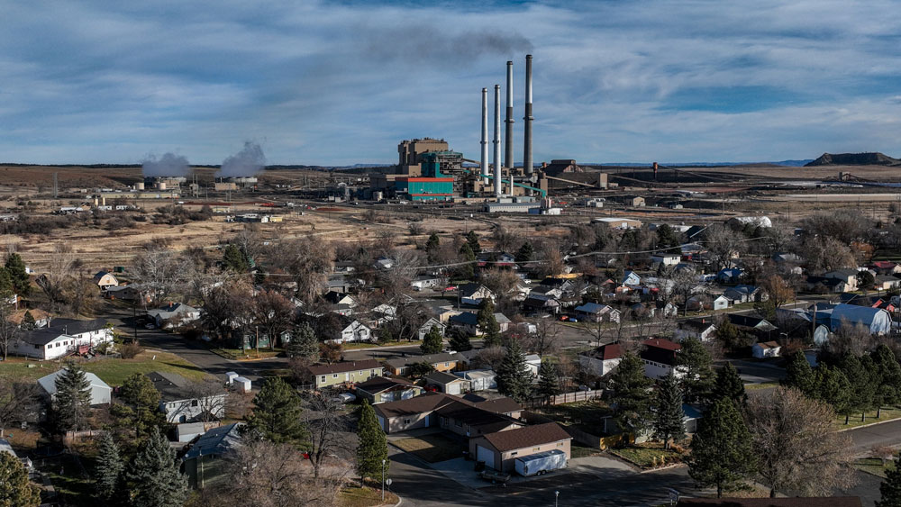 A power plant's smokestacks are visible from miles away in a small town.